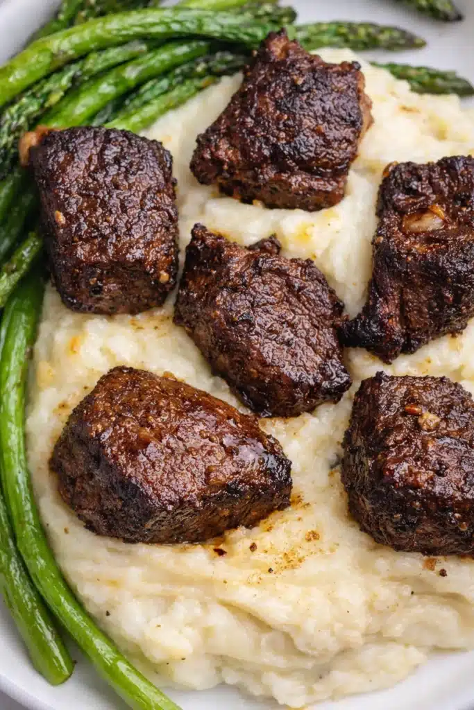 Garlic Butter Steak Bites with Creamy Parmesan Sauce 5 Garlic butter steak bites with crispy sear over mashed potatoes and asparagus