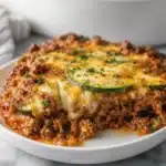 ground beef zucchini bake with melted cheese and marinara on white plate