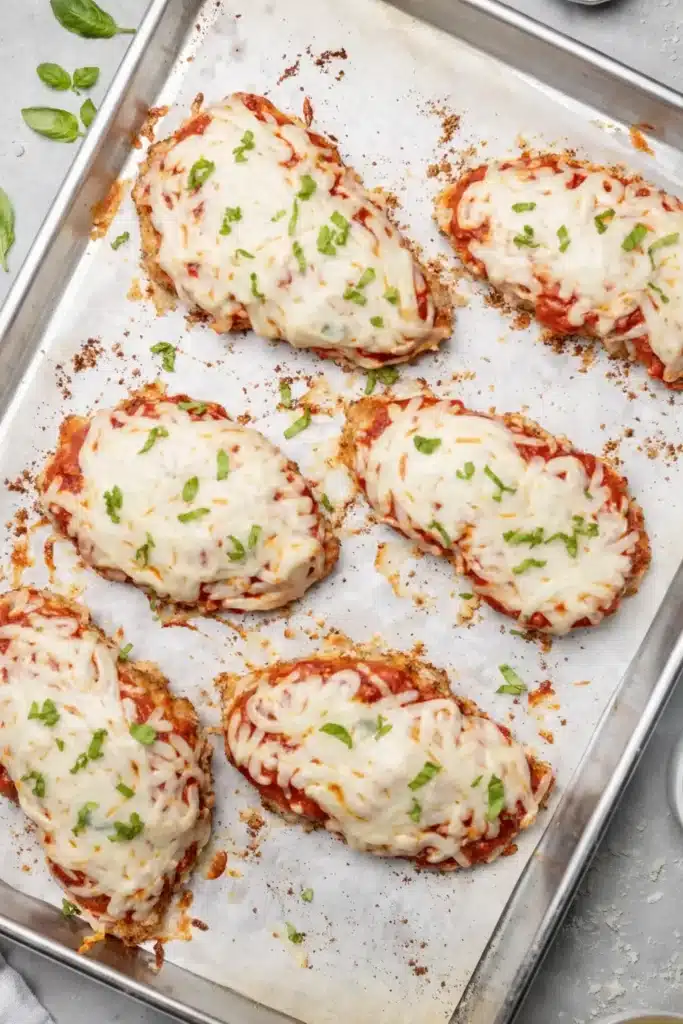 Healthy Baked Chicken Parmesan on baking sheet with melted cheese
