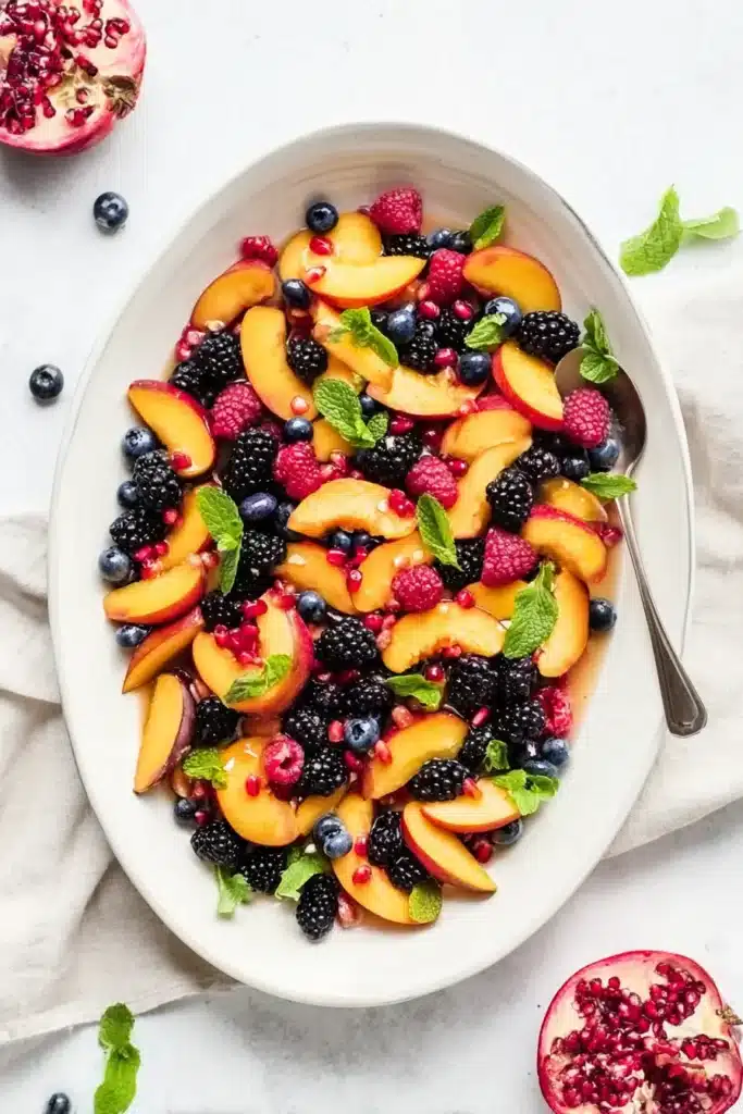 Honey Lime Basil Peach Fruit Salad served on a platter with fresh peaches and berries
