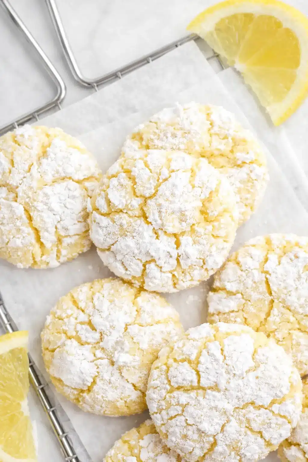 Soft lemon crinkle cookies with powdered sugar and cracked tops on a light surface