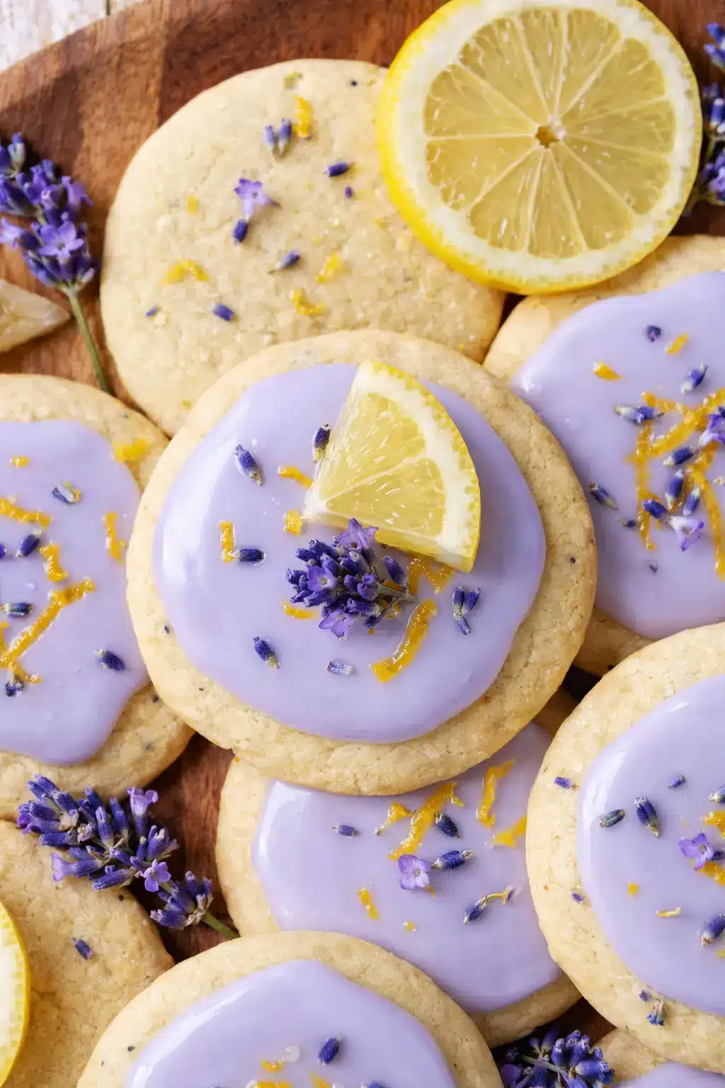 Lemon lavender cookies with purple glaze, lemon slices, and dried lavender on a light surface