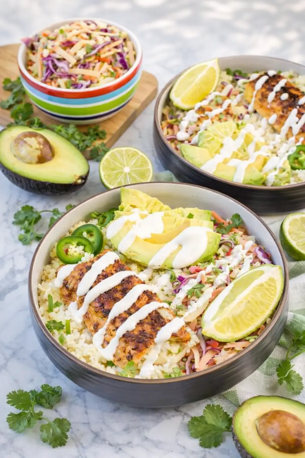 Low carb fish taco bowls with cauliflower rice, avocado, slaw, and creamy lime sauce