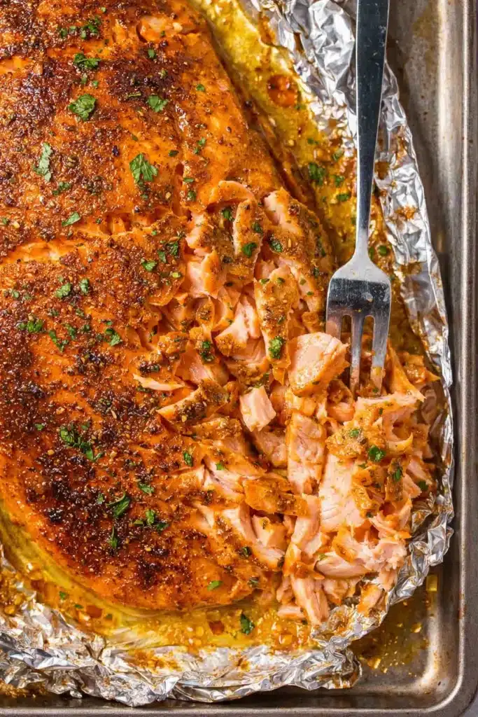 Oven baked salmon flaked with fork showing juicy garlic butter texture