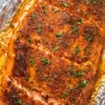 Oven baked salmon fillet with garlic butter and herbs on baking tray