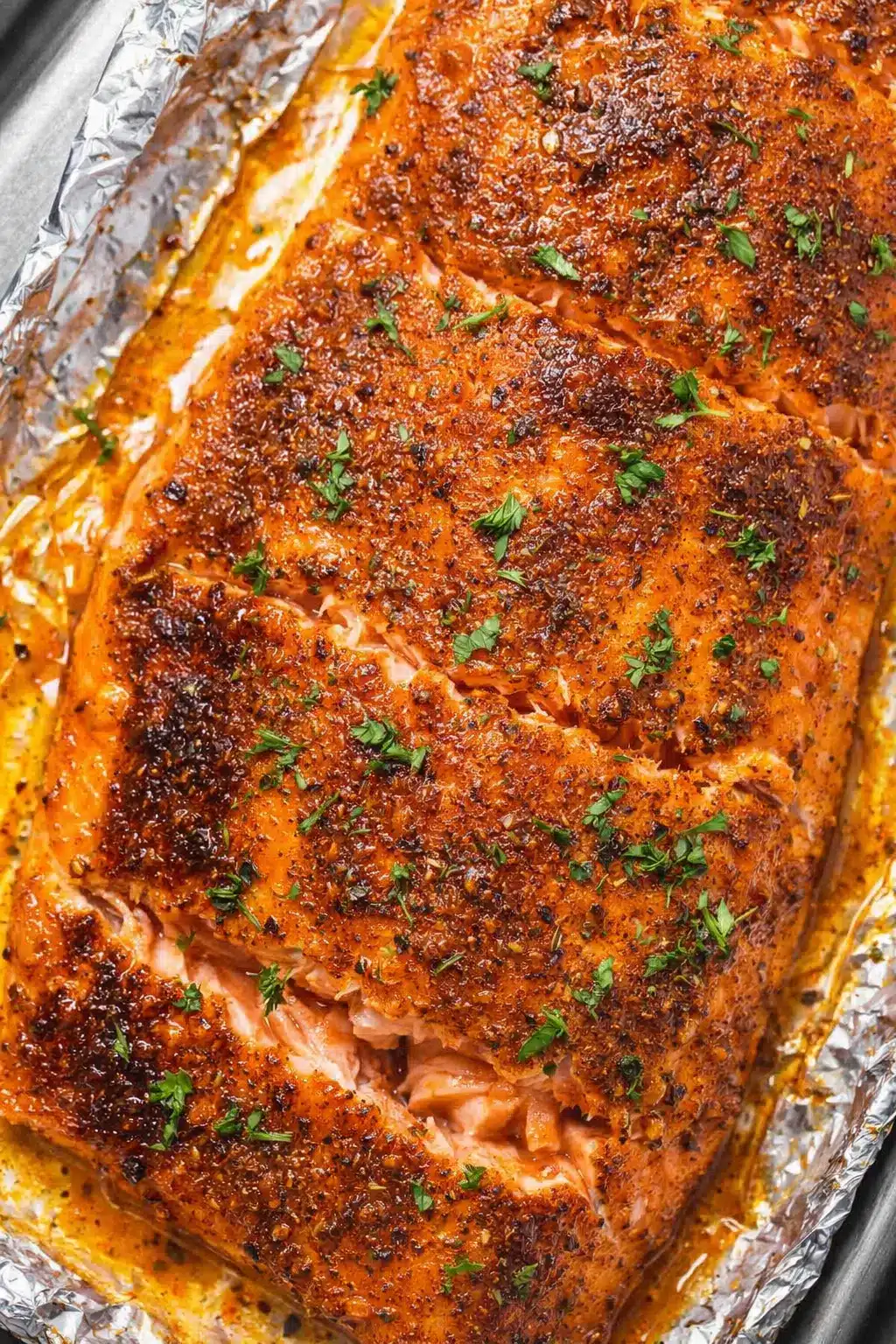 Oven baked salmon fillet with garlic butter and herbs on baking tray