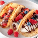 Pancake tacos with fruit, yogurt, and chocolate drizzle on a plate