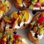 Peach bruschetta with whipped ricotta, tomatoes, basil, and balsamic glaze on toasted bread