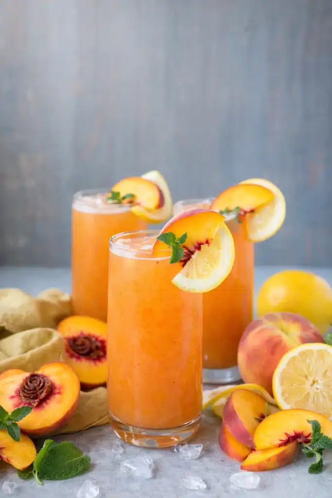 Peach Lemonade Easy Amazing Summer Drink Recipe 6 Peach lemonade glasses with fresh peaches, lemon slices, and mint garnish