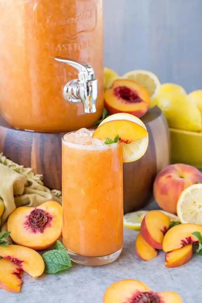 Peach Lemonade Easy Amazing Summer Drink Recipe 5 Peach lemonade in glass with fresh peaches, lemon slices, and mint