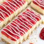 Philadelphia cheesecake bars with strawberry topping and white chocolate drizzle