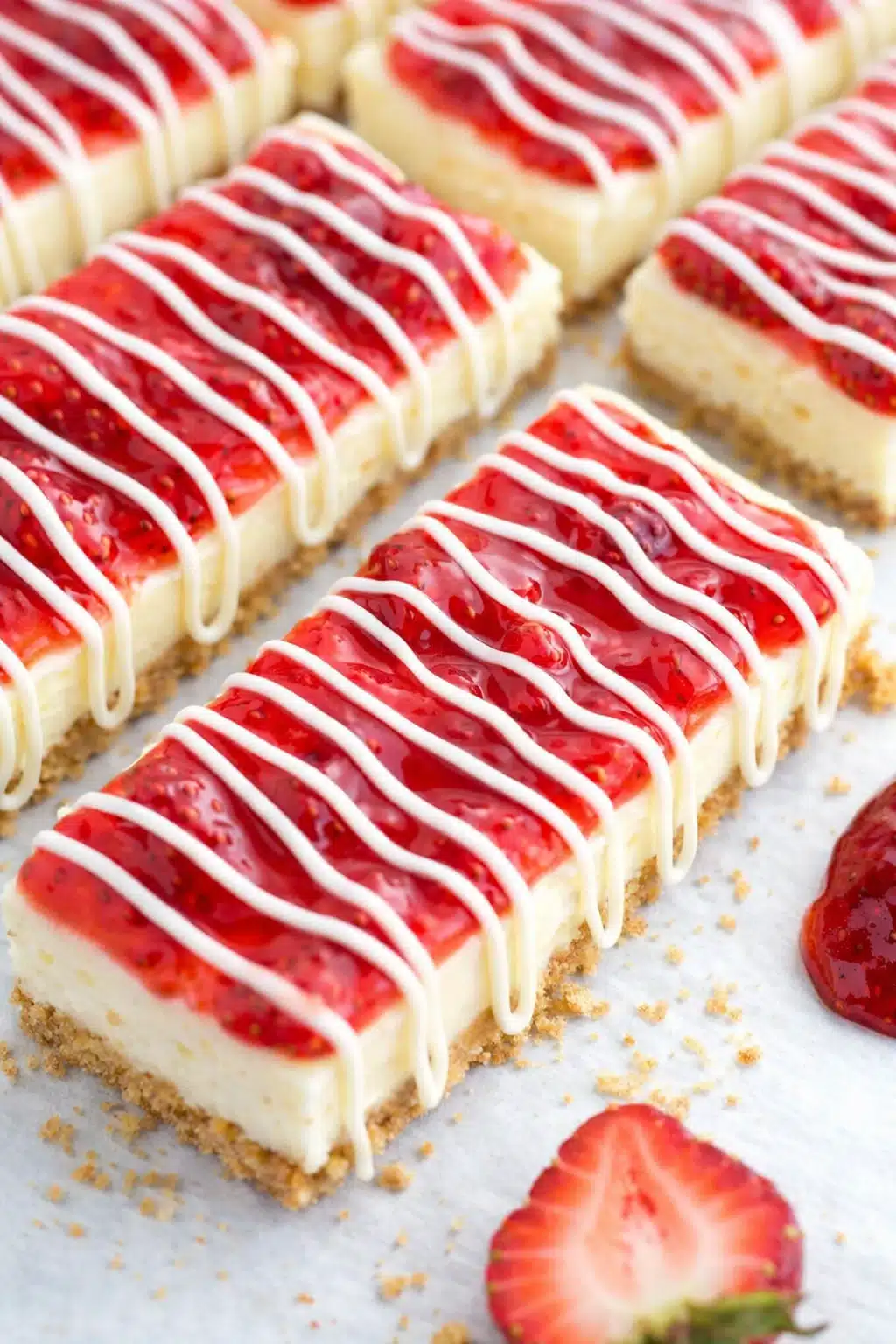 Philadelphia cheesecake bars with strawberry topping and white chocolate drizzle
