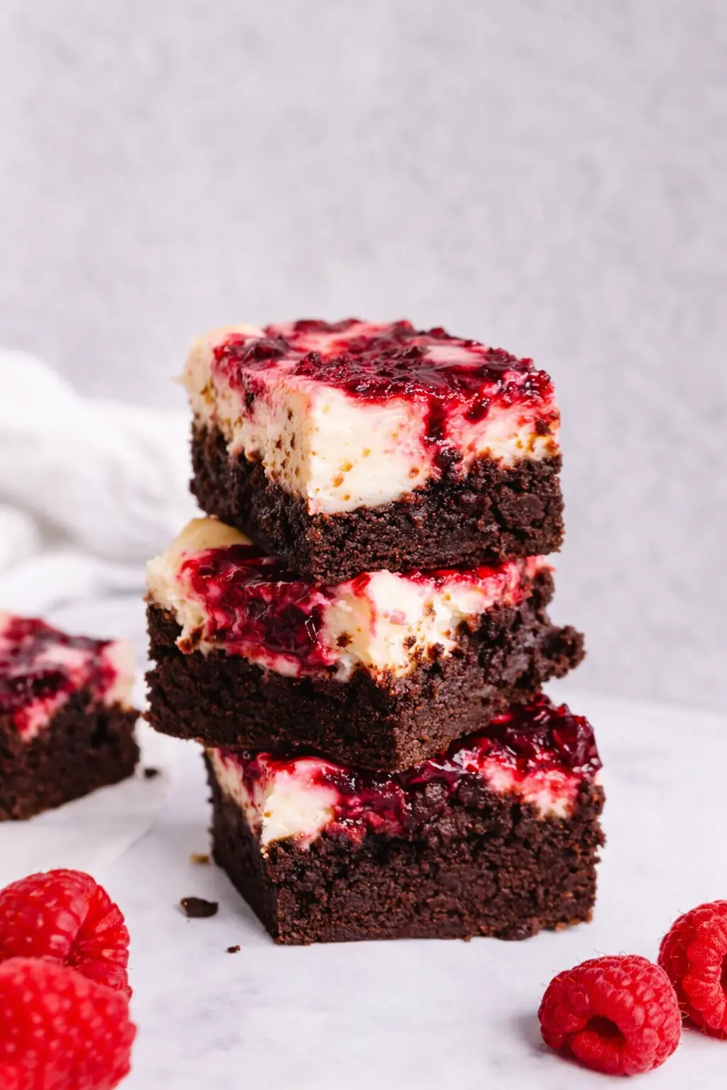 Raspberry cheesecake brownies stacked with fudgy chocolate layers and creamy swirl
