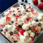 Red White and Blue Cheesecake Salad with strawberries blueberries and marshmallows in creamy mixture