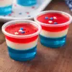 Red white and blue jello shots in layered cups with star sprinkles for 4th of July party