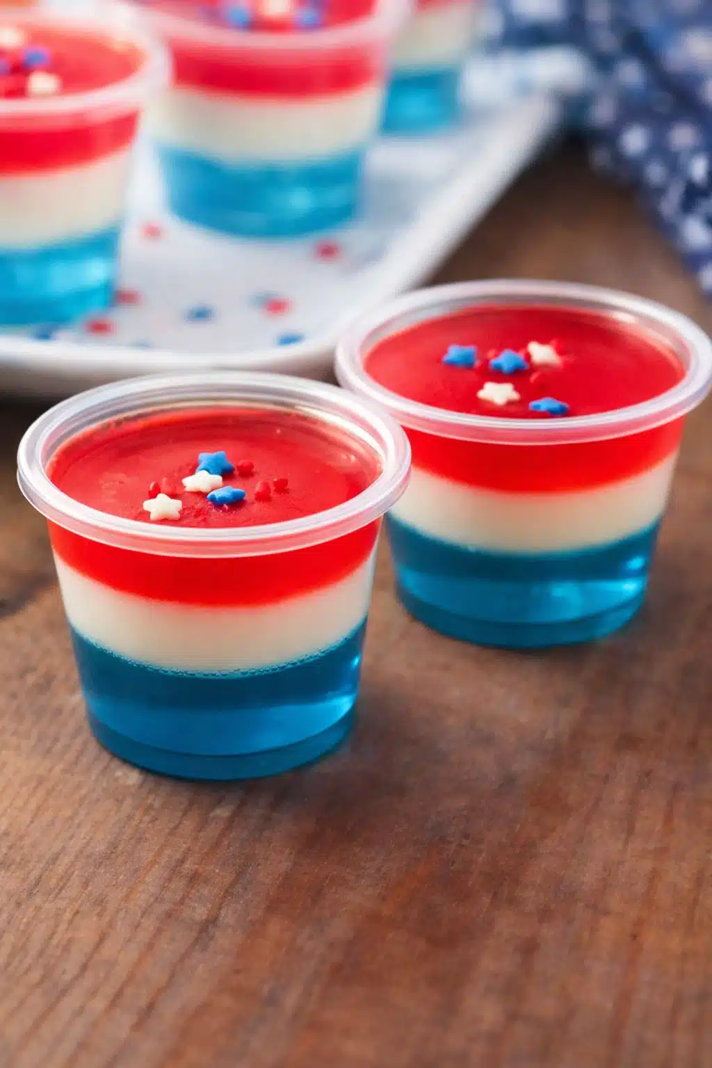 Red white and blue jello shots in layered cups with star sprinkles for 4th of July party
