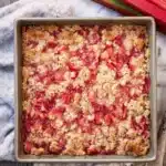 Rhubarb dessert with jello and crumb topping in baking dish with fresh rhubarb