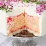 Rose rhubarb layer cake with floral decoration and creamy filling on cake stand