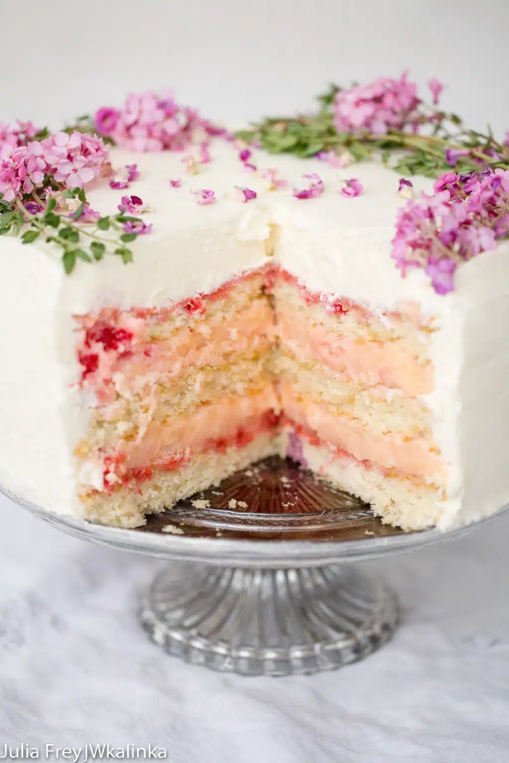 Rose rhubarb layer cake with floral decoration and creamy filling on cake stand