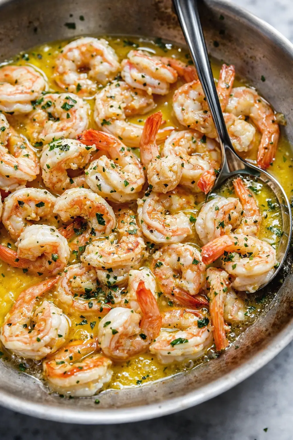Shrimp scampi in garlic butter sauce with parsley in skillet