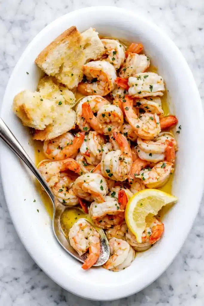 Shrimp Scampi served with bread and lemon in white dish