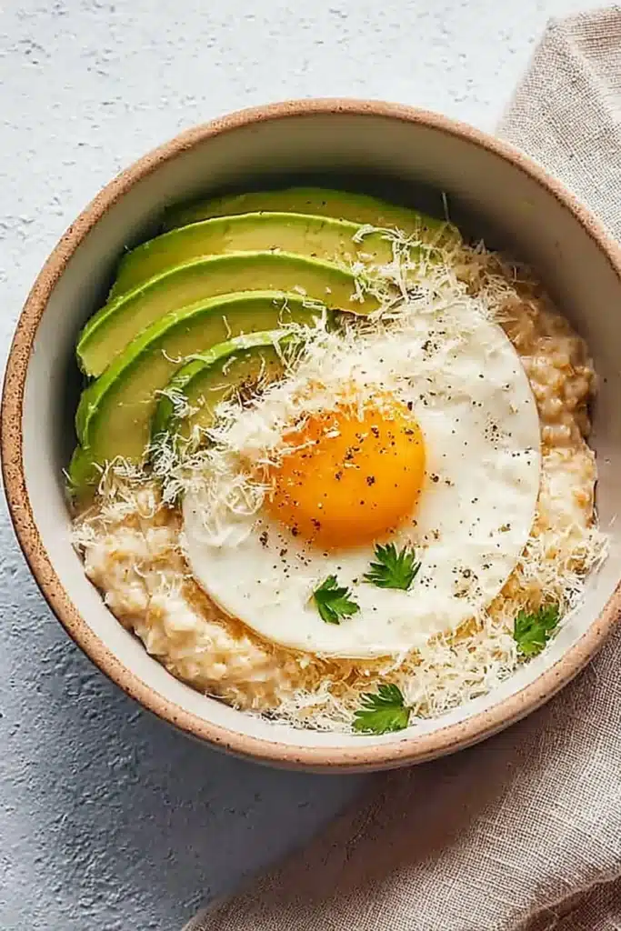 Simple savory avocado oatmeal with fried egg and cheese in a ceramic bowl