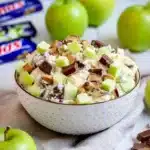 Snickers salad with green apples and chocolate pieces in a creamy dessert bowl