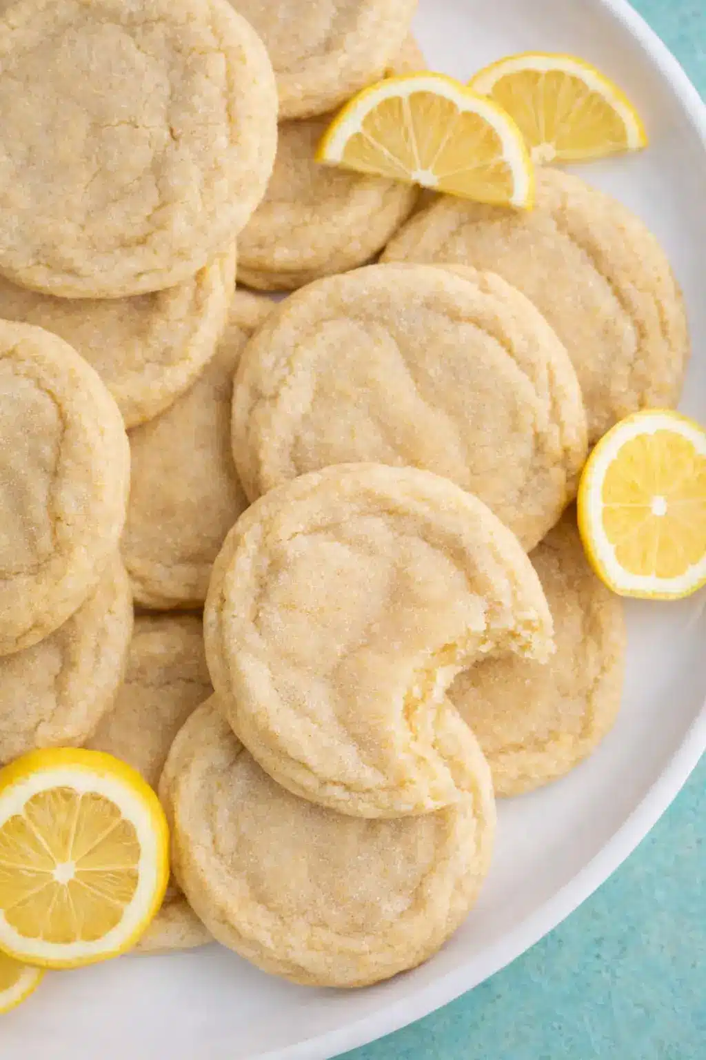 soft lemon sugar cookies with chewy centers and fresh lemon slices on a plate