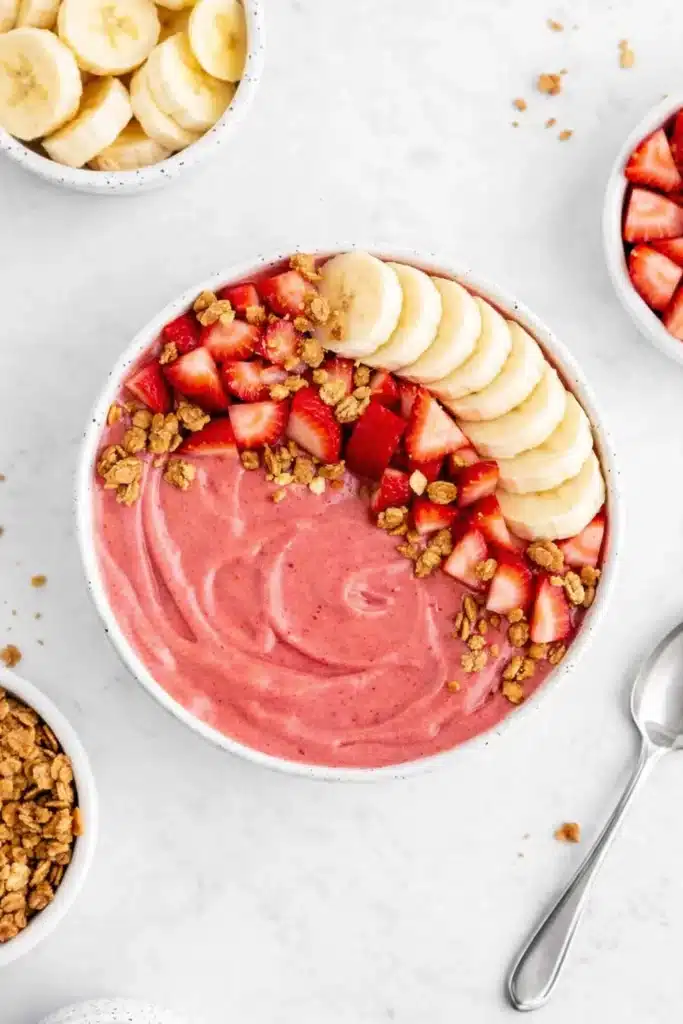 Strawberry banana smoothie bowl with fresh fruit and granola toppings