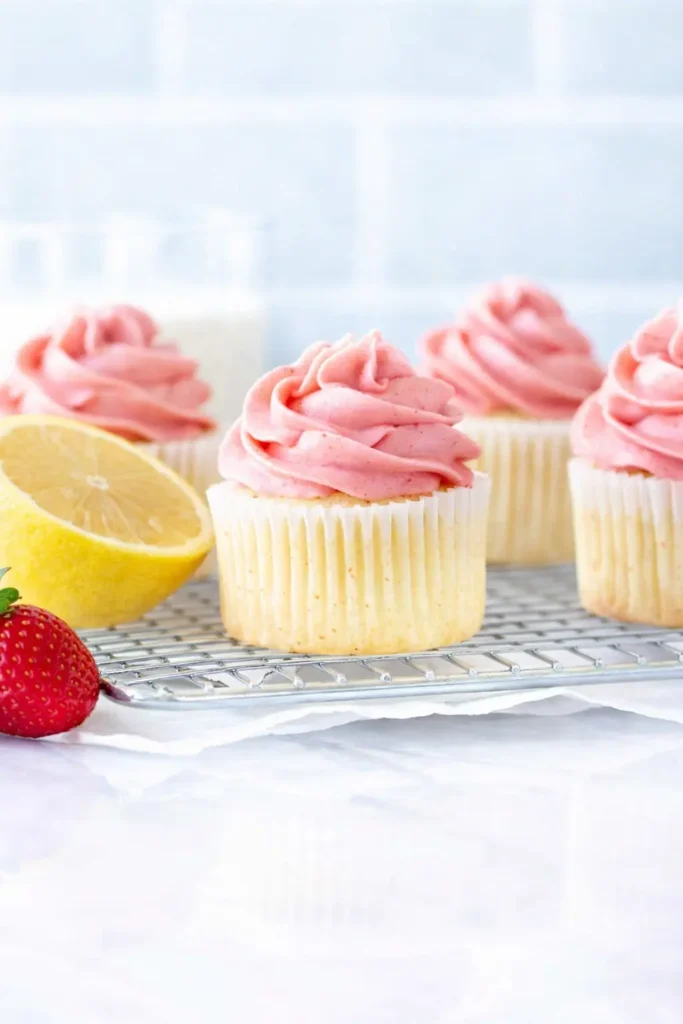 Strawberry lemonade cupcakes with pink frosting and fresh lemon and strawberries