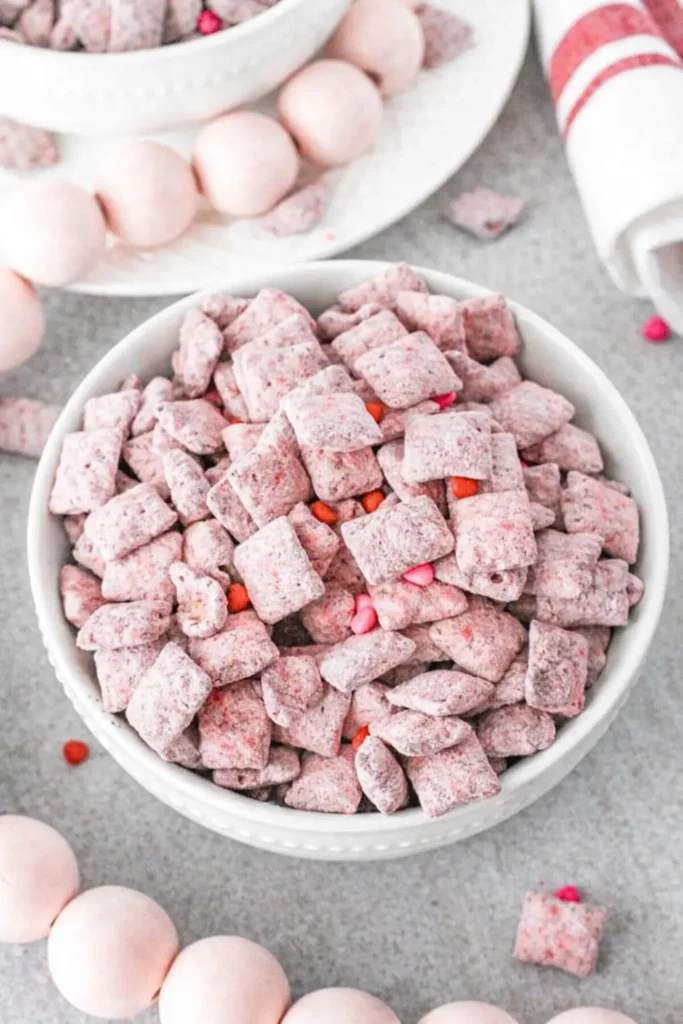 Strawberry muddy buddies snack mix coated in pink sugar in a white bowl