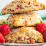 Strawberry rhubarb scones with flaky crust and fresh strawberries on a plate