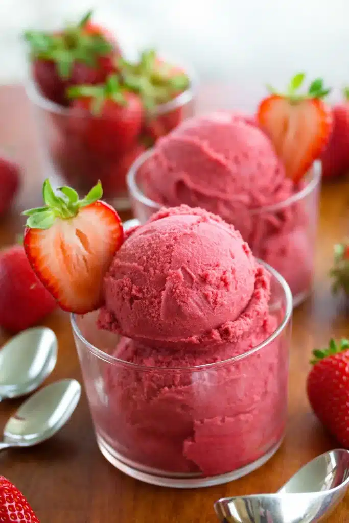 Strawberry Sorbet in glass cup with fresh strawberries on wooden table