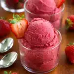 Fresh strawberry sorbet scoops in bowls with ripe strawberries and natural light