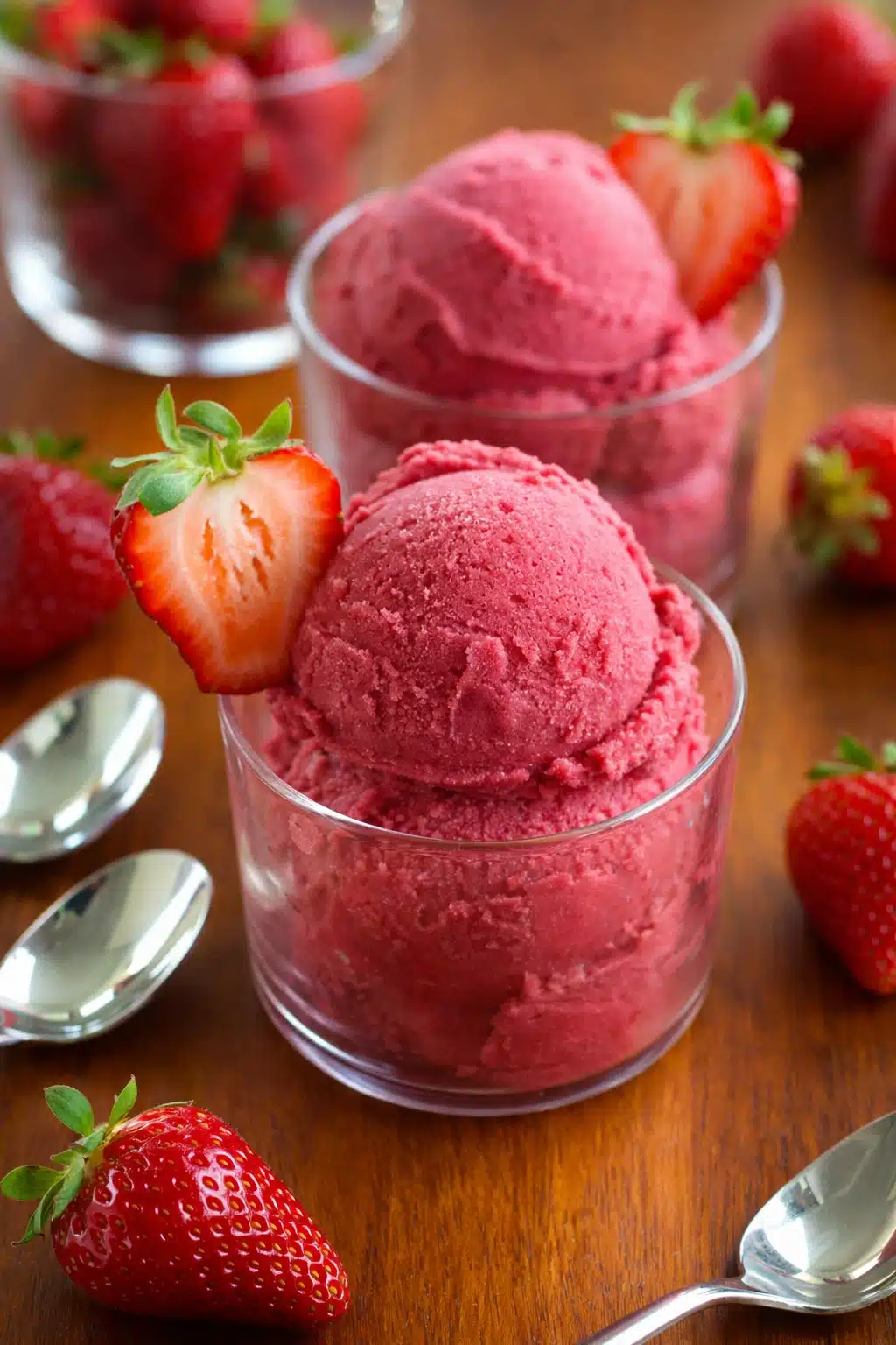 Fresh strawberry sorbet scoops in bowls with ripe strawberries and natural light
