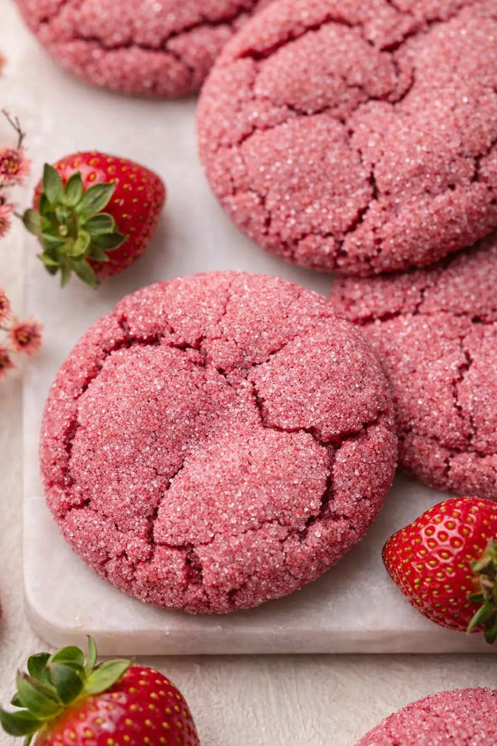 Soft chewy strawberry sugar cookies with crackled tops and sugar coating on a plate with fresh strawberries