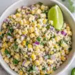 Street corn salad with Greek yogurt, corn, cilantro, lime, and red onion in a bowl