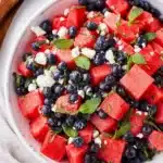 Watermelon feta salad with blueberries, mint, and lime in a white bowl