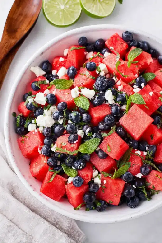 Watermelon feta salad with blueberries, mint, and lime in a white bowl