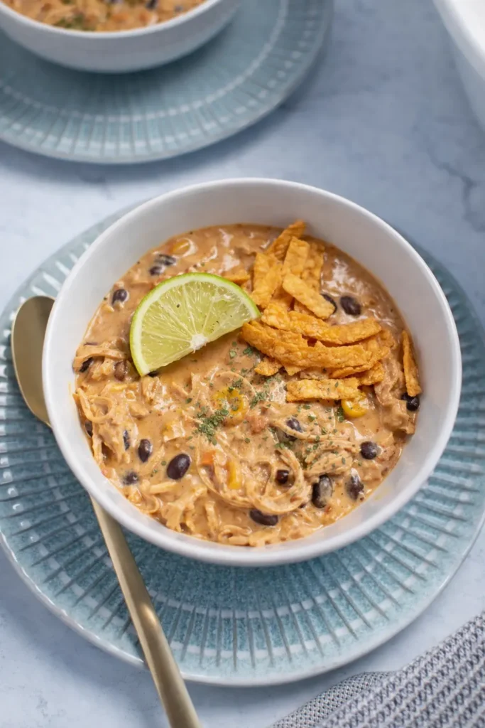 Creamy white chicken chili with tortilla strips and lime in a bowl