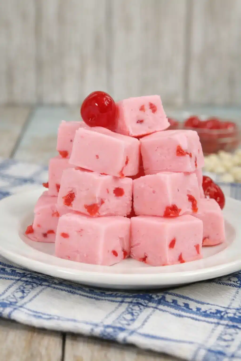 White chocolate cherry fudge cubes stacked on a plate with glossy cherry topping