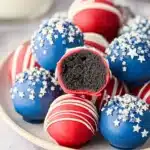 4th of July Oreo balls with red and blue coating and white sprinkles on a plate