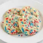 Soft 4th of July Sprinkle Cookies with red white and blue sprinkles stacked on parchment paper