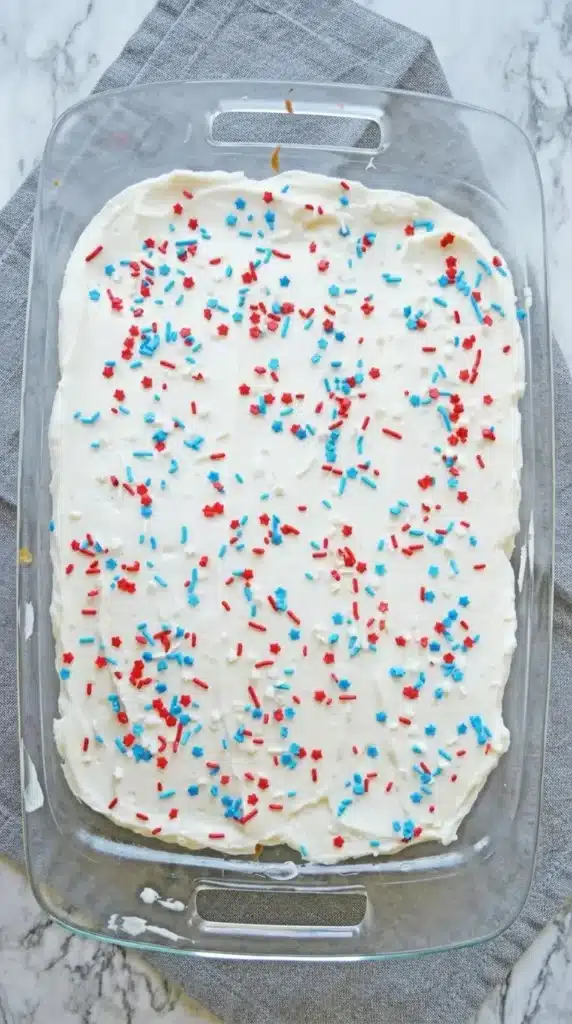 4th Of July Poke Cake Recipe in glass baking dish with patriotic sprinkles