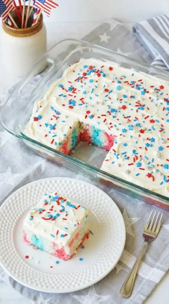 Close up 4th Of July Poke Cake Recipe slice with patriotic sprinkles and creamy frosting