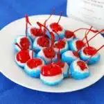 Boozy cherry bombs dipped in white chocolate and blue sugar on a plate