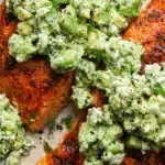 Baked salmon with avocado and feta topping on a ceramic dinner plate