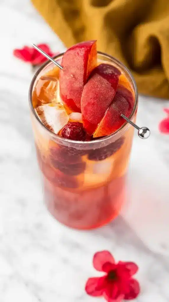 Bellini Peach Raspberry Iced Tea with peach garnish and fresh raspberries