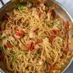 Buttered lobster pasta with spaghetti, lobster, and cherry tomatoes in skillet
