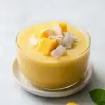 Creamy coconut mango pudding topped with fresh mango cubes and coconut flakes